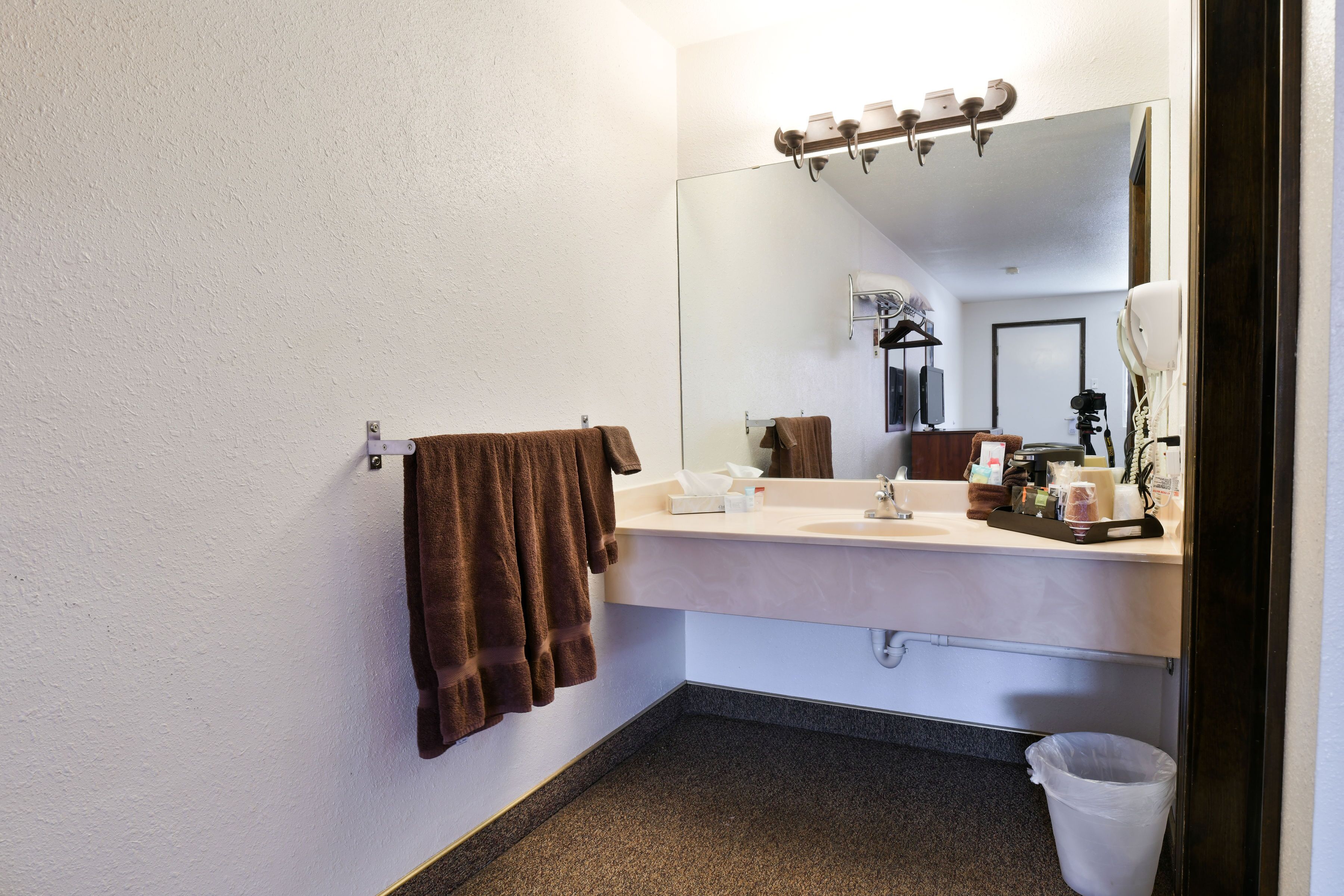 Un baño con un lavabo blanco, un espejo y un perchero para toallas.