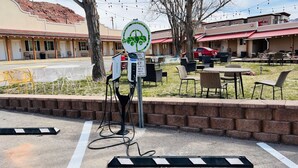 A hotel with outdoor seating, a parking meter, and a sign indicating electric vehicle charging. - Adventure Inn & Motel (Moab)