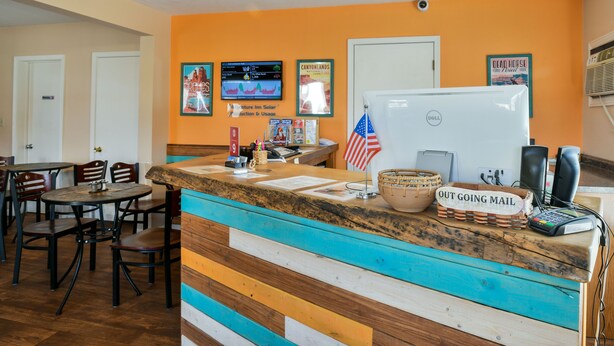 A reception desk with a sign reading "OUT GOING MAIL," a whiteboard, and a flag. - Adventure Inn & Motel (Moab)