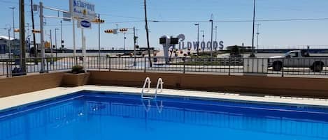 A swimming pool with a clear view of Newport Beach and the Wildwoods sign in the background.