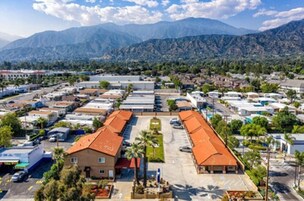 Zona comercial con varios edificios, estacionamientos y montañas al fondo.