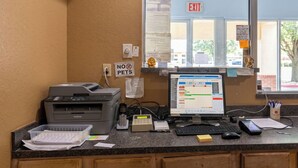 Un comptoir d’accueil équipé d’un ordinateur, d’une imprimante et de divers fournitures de bureau.