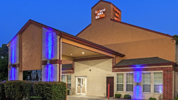 Un hôtel à la façade en briques, avec une enseigne indiquant « Garland Inn & Suites » et une entrée abritée.