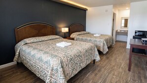 Une chambre d’hôtel avec deux lits, un bureau et un four à micro-ondes.