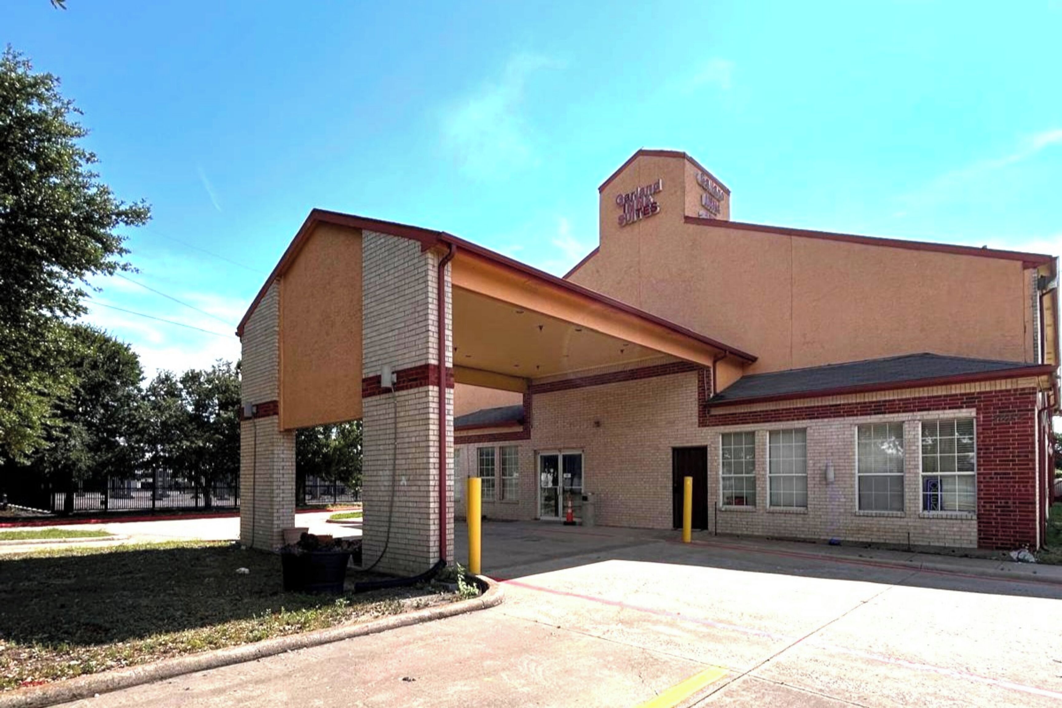 A building with a flat roof, a covered entrance, and a sign indicating it is a hotel.