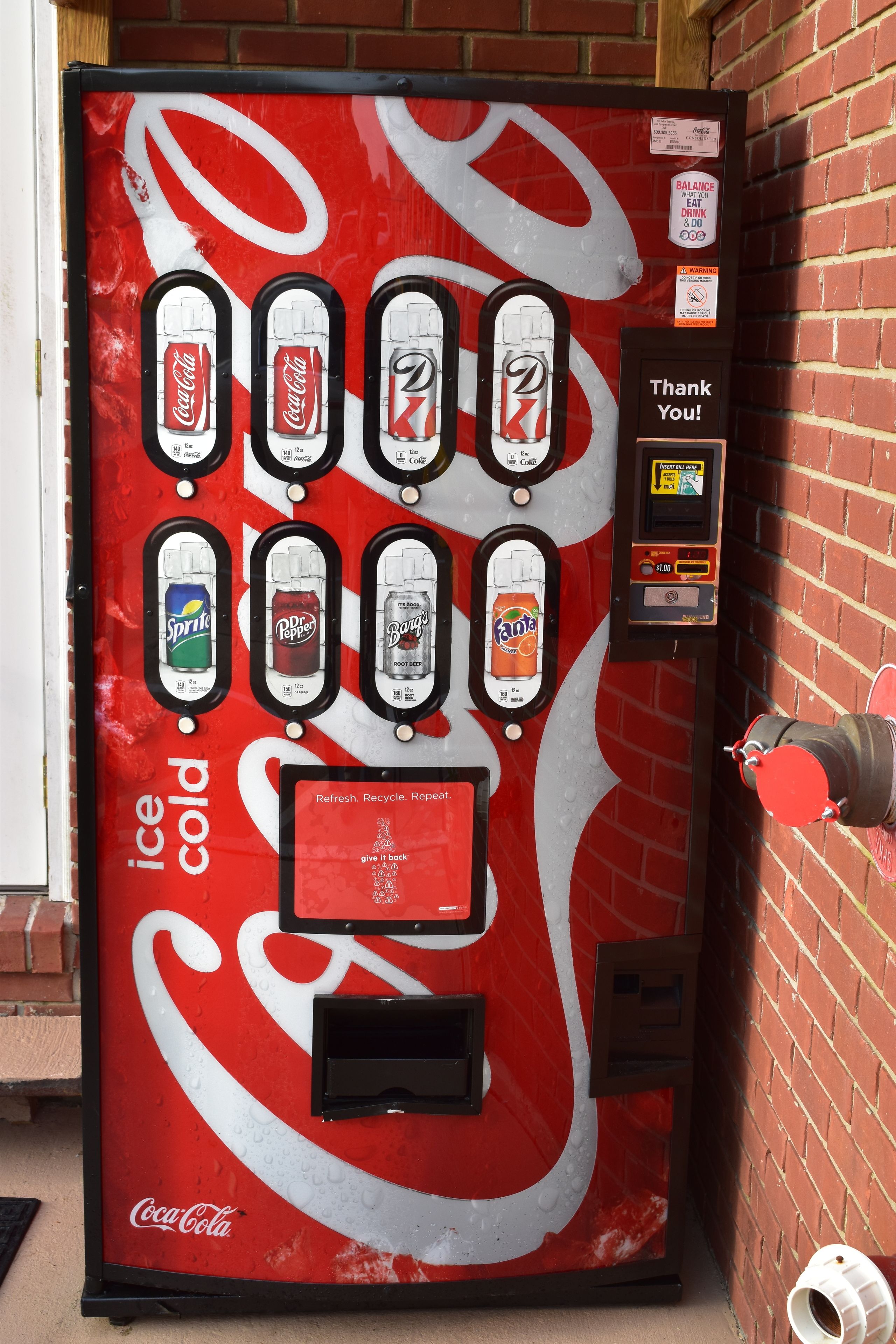 A Coca-Cola branded vending machine with multiple beverage options, a payment interface, and a 'Thank You!' sign.