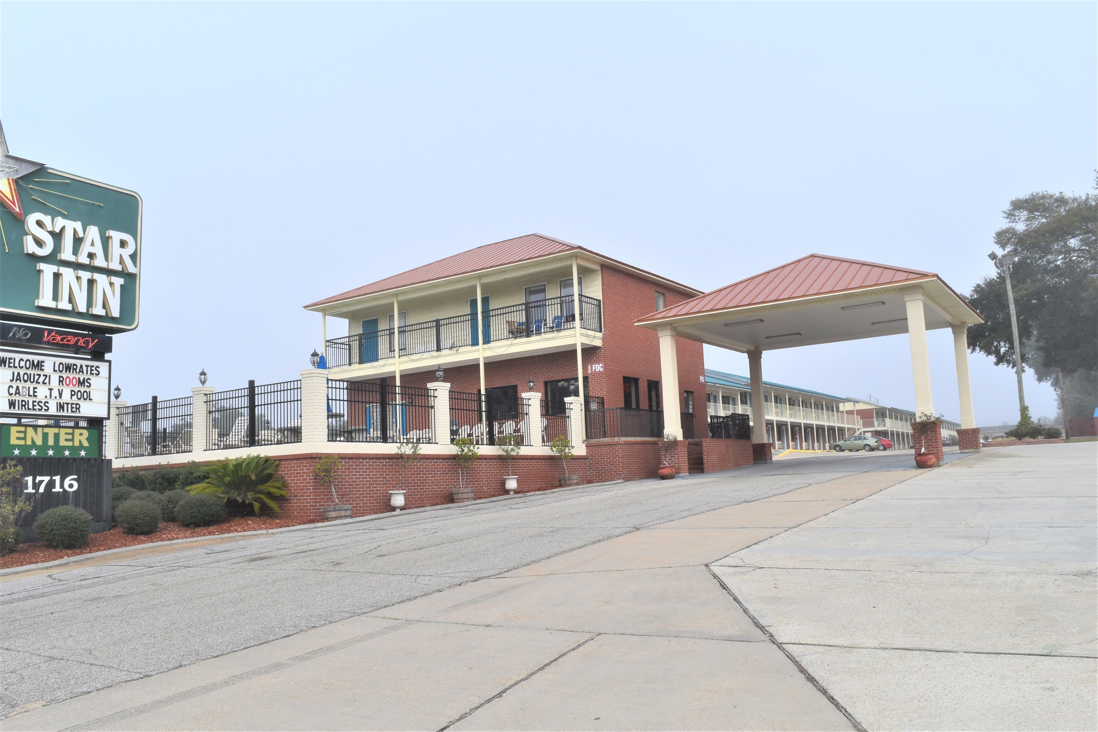 A hotel with a signboard indicating 'Star Inn' and 'No Vacancy'. The building has a red roof, a covered entrance, and a fenced balcony.