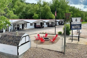 Un motel con un área de estar exterior cercada, una fogata y un letrero que indica que es The Brookside Motel.