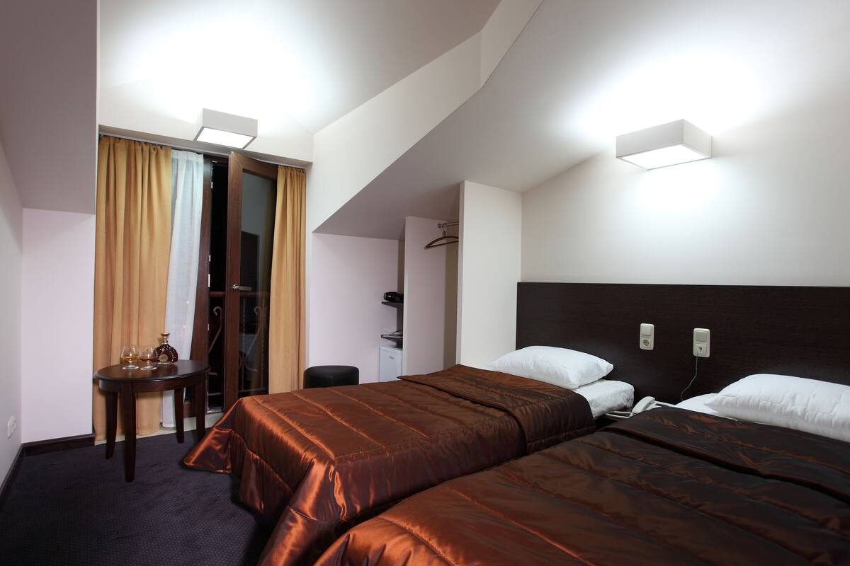 Habitación de hotel con dos camas, un escritorio, una silla y un baño.