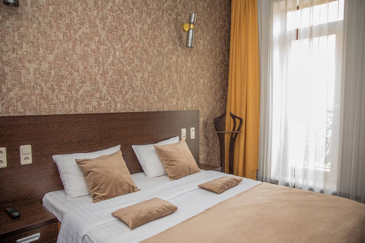Habitación de hotel con una cama grande, cabecera de madera y una lámpara fijada a la pared.