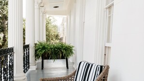 A covered porch with wicker furniture and potted plants. - Henry Howard Hotel (New Orleans)