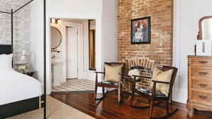 A bedroom with a four-poster bed, a brick fireplace, and a wooden dresser. - Henry Howard Hotel (New Orleans)