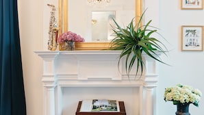 A fireplace with a mirror above it, a saxophone, and a book on a small table in front of the fireplace. - Henry Howard Hotel (New Orleans)