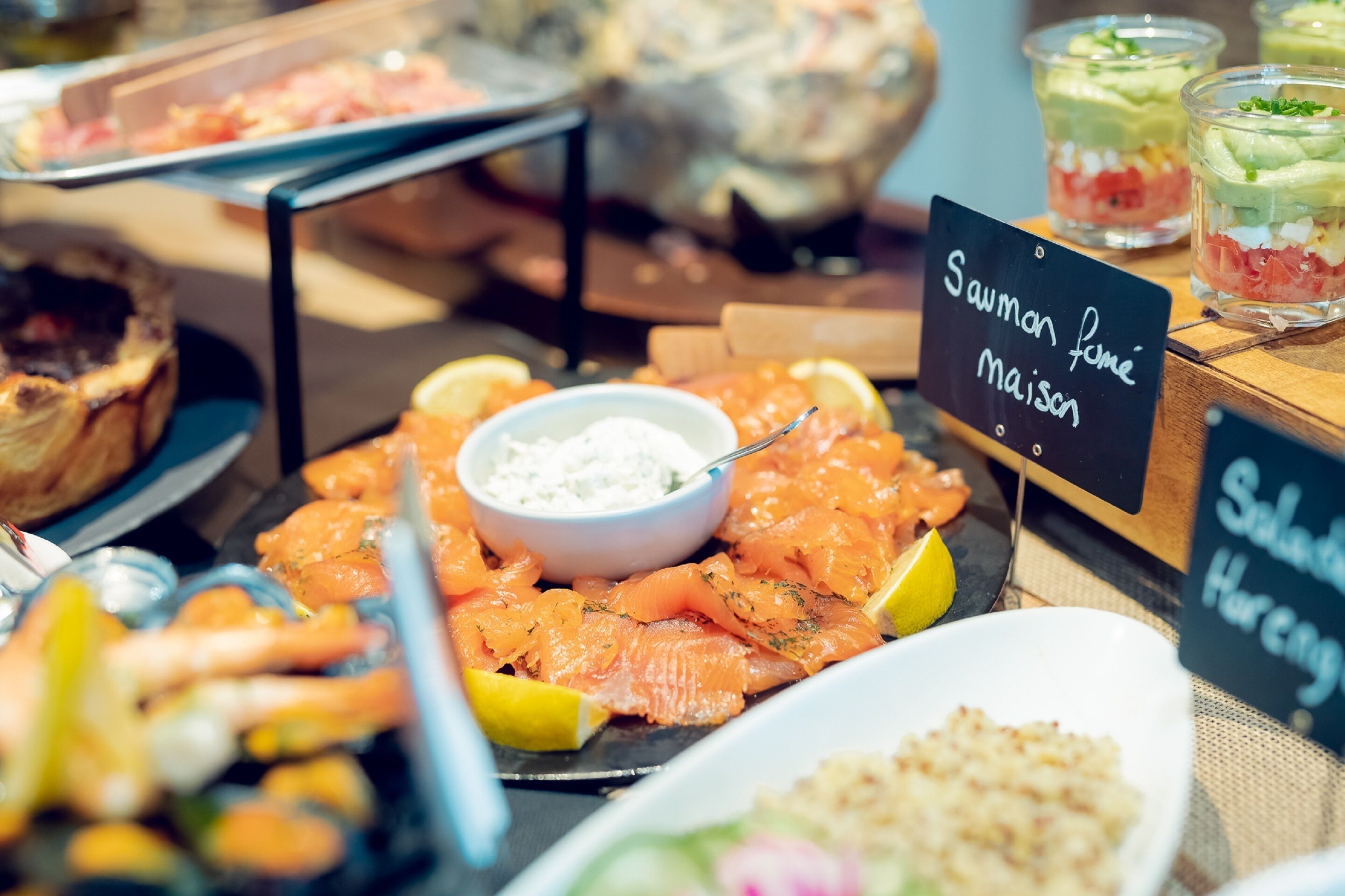 Een buffet met diverse gerechten, waaronder zalm, citroenpartjes en een bakje dipsaus.