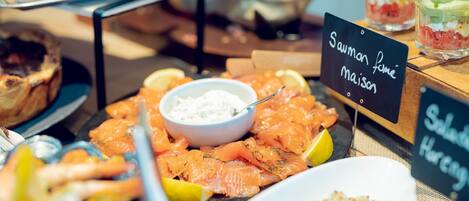 Een buffet met diverse gerechten, waaronder zalm, citroenpartjes en een bakje dipsaus.