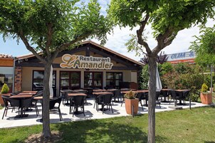 Un restaurante llamado 'Restaurant Amandier' con terraza y zona de patio.