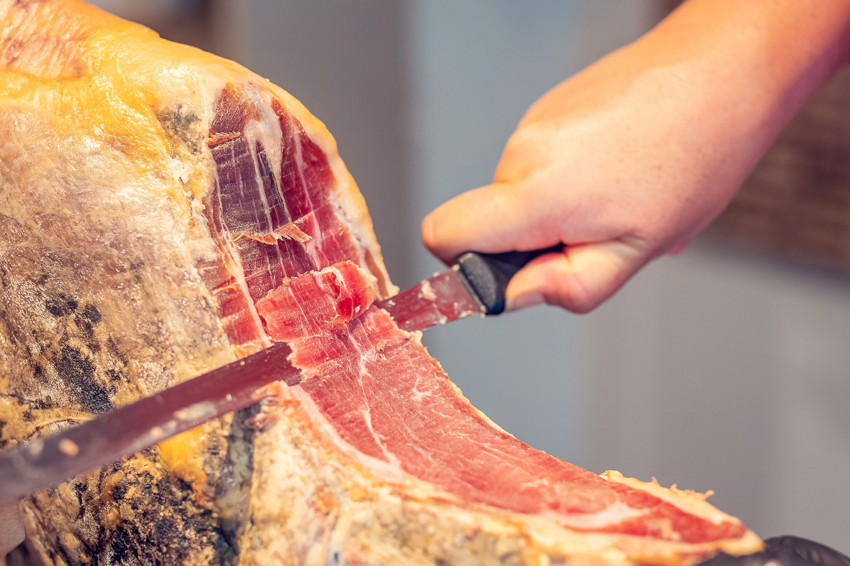 A person carving a large piece of meat.