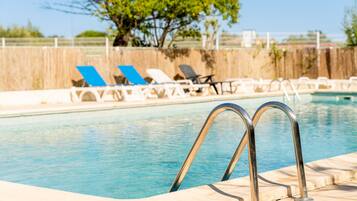 A swimming pool with lounge chairs and metal pool ladders.