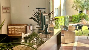 Een receptiebalie met een computer, een plant en rieten meubels.