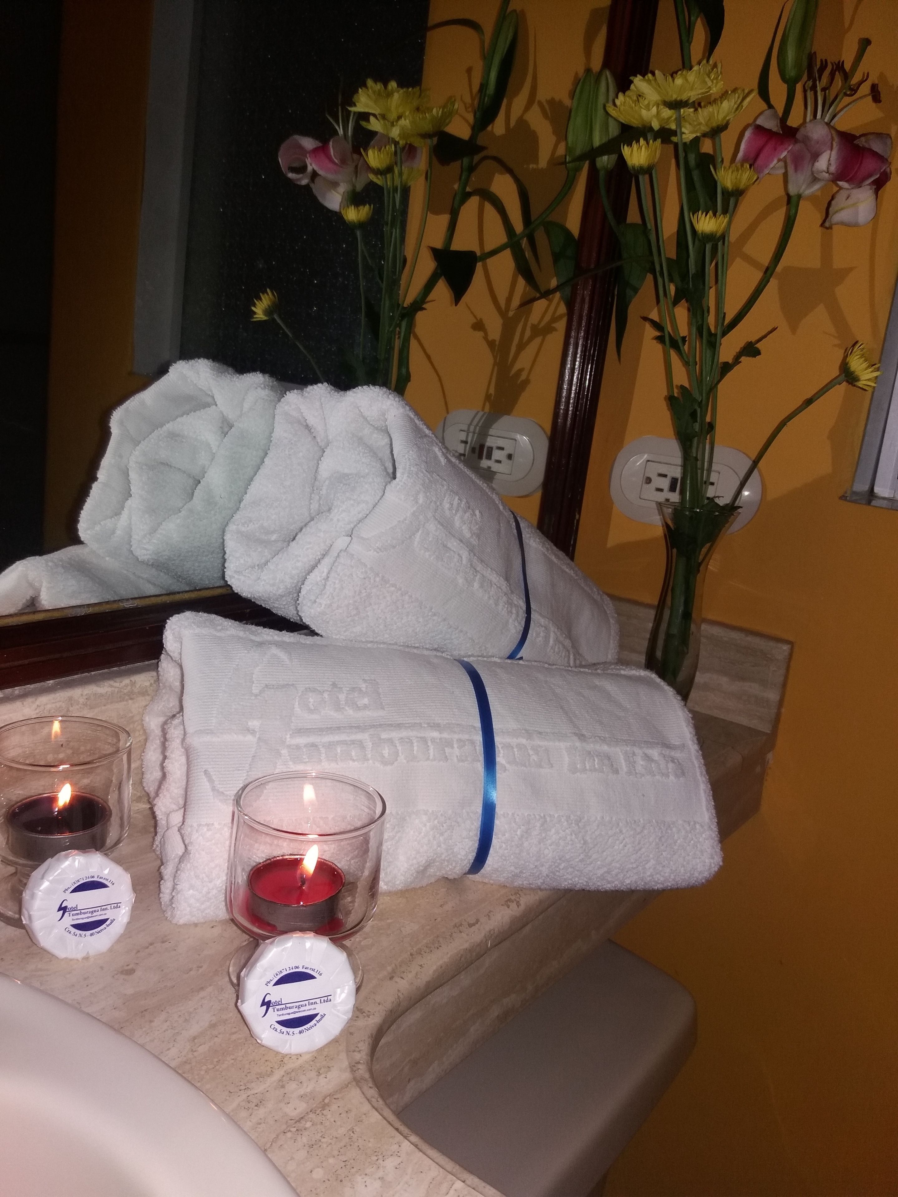 Un meuble-lavabo de salle de bain agrémenté de serviettes, de bougies et d’un vase de fleurs.