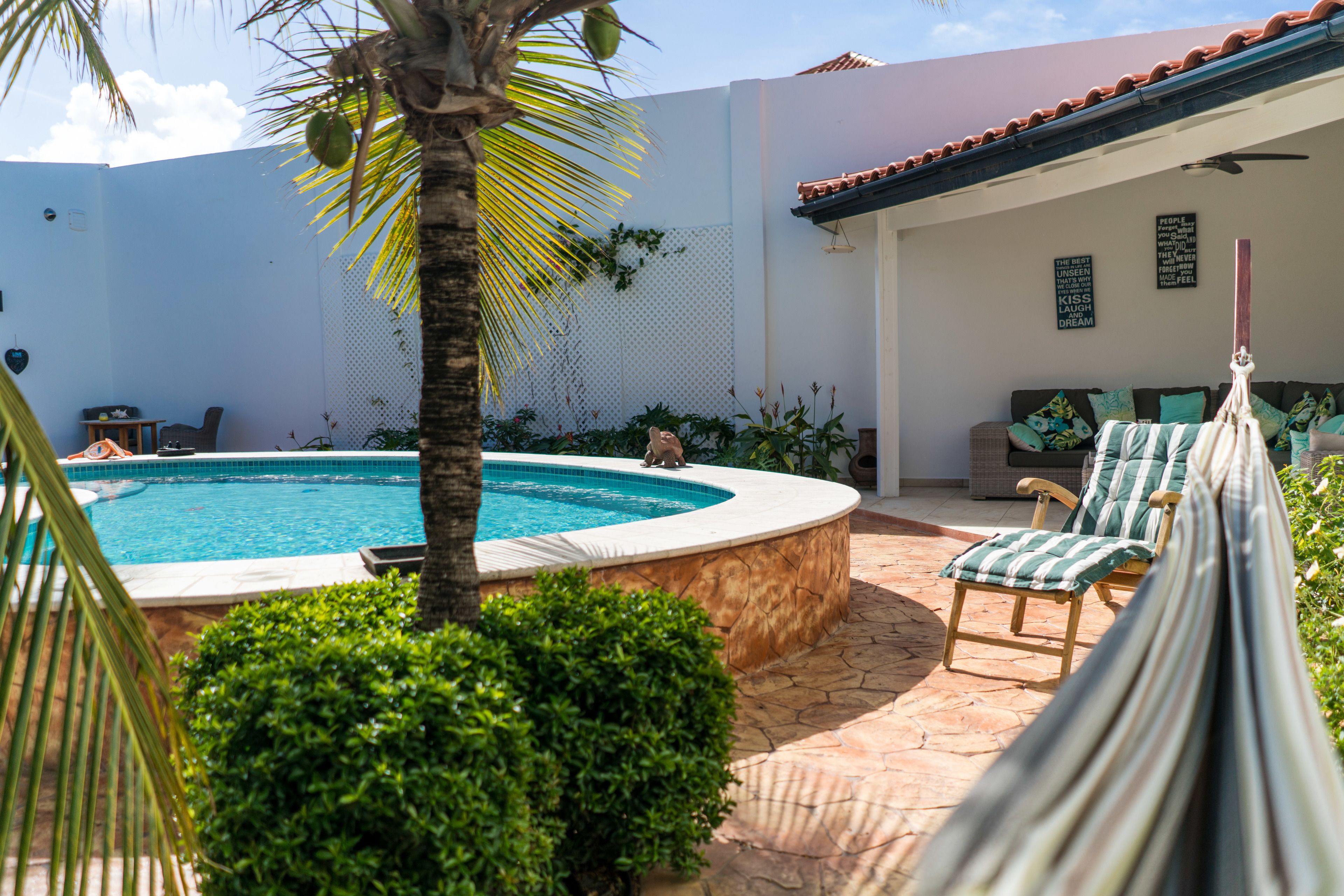 A pool area with a hot tub, lounge chairs, and a hammock.