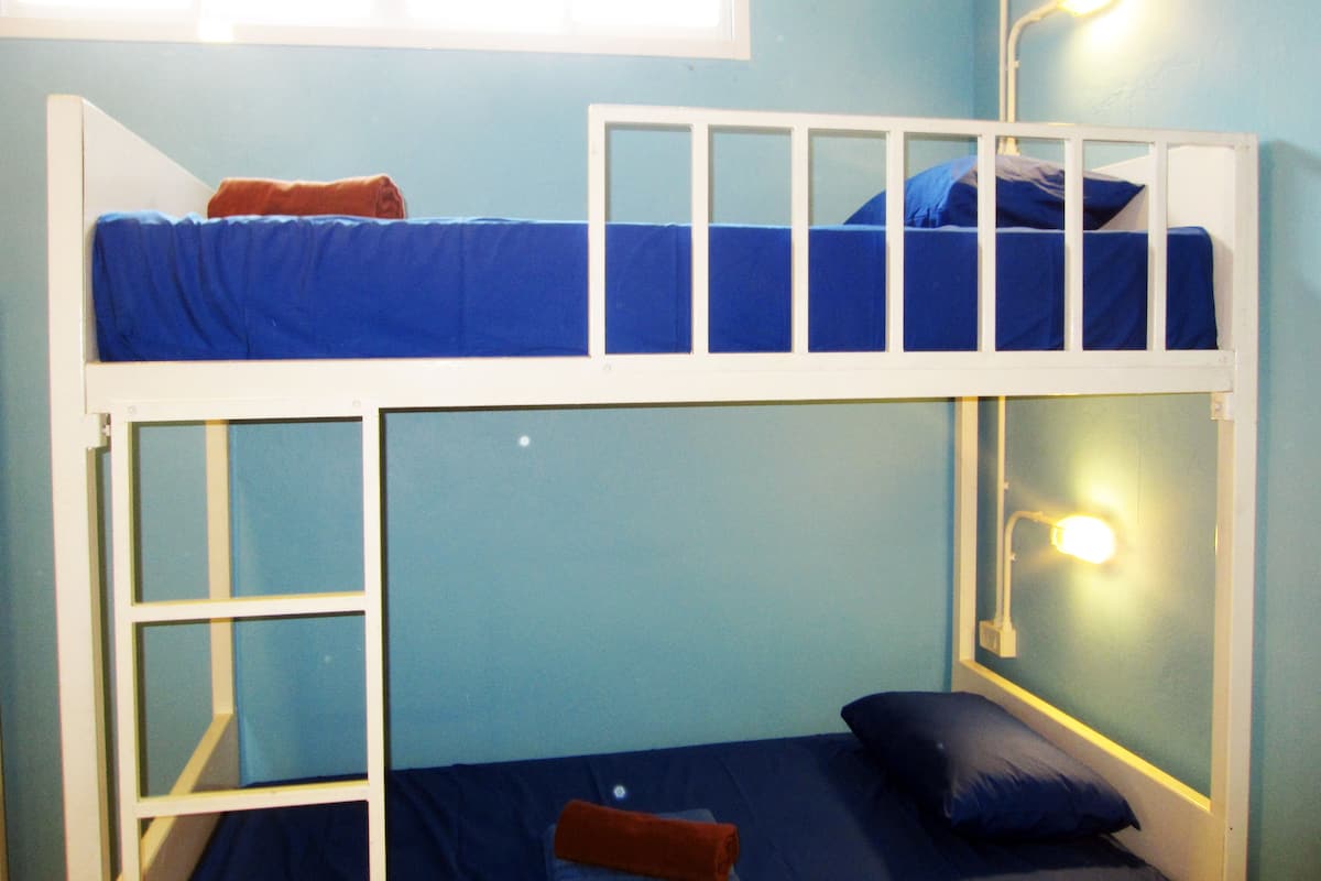 A bunk bed room with two beds, a window, and a wall-mounted light fixture.