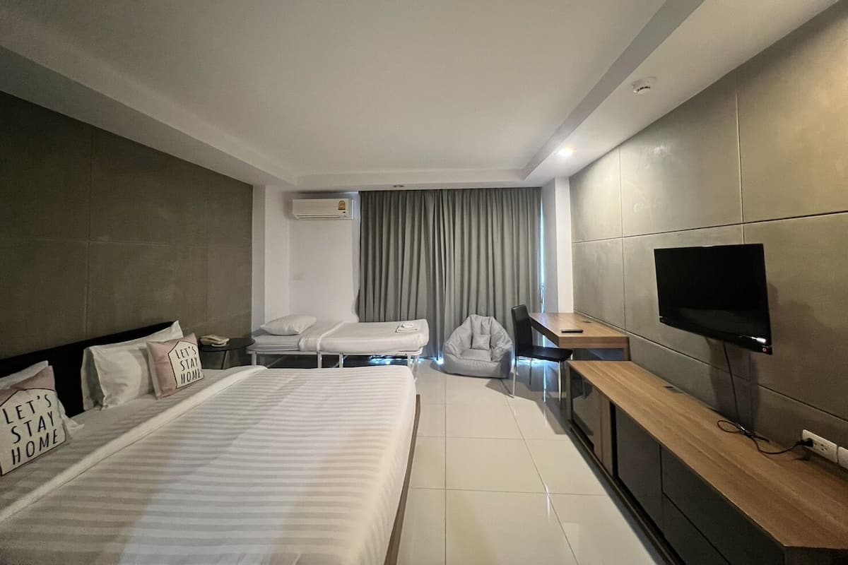 Una habitación de hotel moderna con una cama grande, un escritorio, un televisor de pantalla plana y una zona de estar.