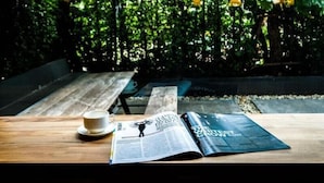 A wooden table with a cup and a magazine. - WE GRAND EVER 9 (Nakhon Ratchasima)
