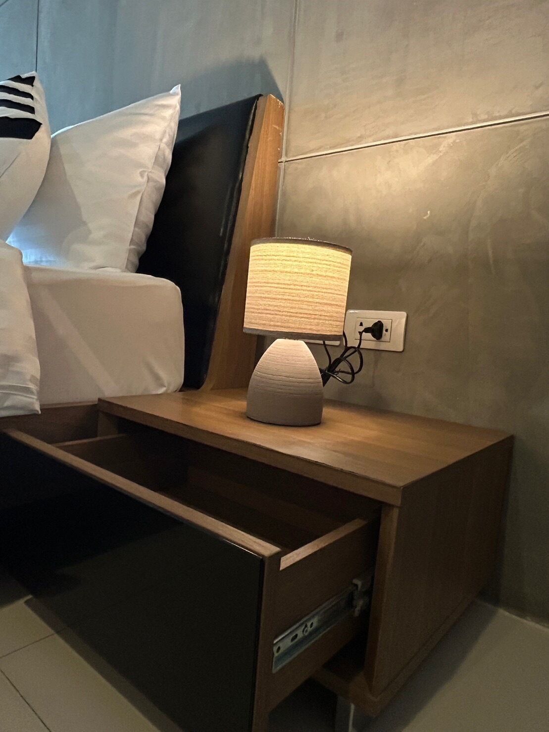 Un dormitorio con una cama, una mesita de noche con lámpara y una cómoda.