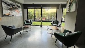 A modern interior with a large window, two green armchairs, a round table, and abstract art on the walls. - WE GRAND EVER 9 (Nakhon Ratchasima)