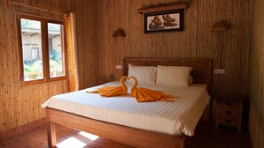 Una stanza con rivestimento in legno, un letto, un quadro appeso al muro e una finestra con tende.