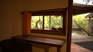 Una panca e una sedia di legno vicino a una finestra con vista su un giardino.