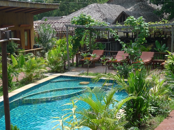 Una piscina al aire libre, sillones reclinables de piscina