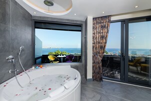 Ein modernes Badezimmer mit einer großen Badewanne, einer Dusche und Blick auf Stadt und Meer.