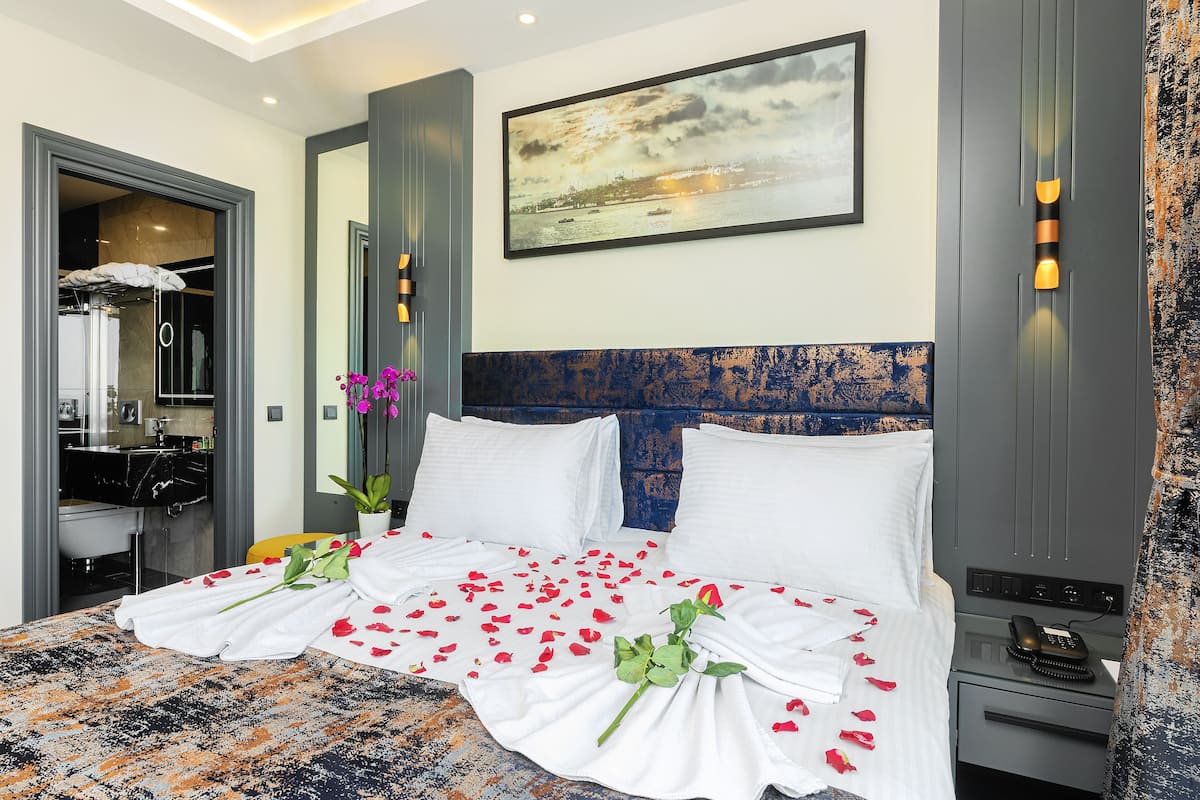 Ein Hotelzimmer mit Bett, Nachttisch, Telefon, einem Gemälde und einem durch eine geöffnete Tür einsehbaren Badezimmer.