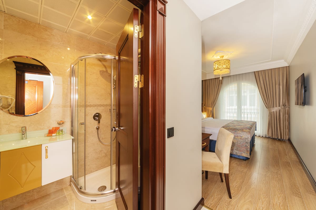 Ein Hotelzimmer mit Dusche, einem Bett, einem Essbereich und einem Badezimmer mit Waschtisch.