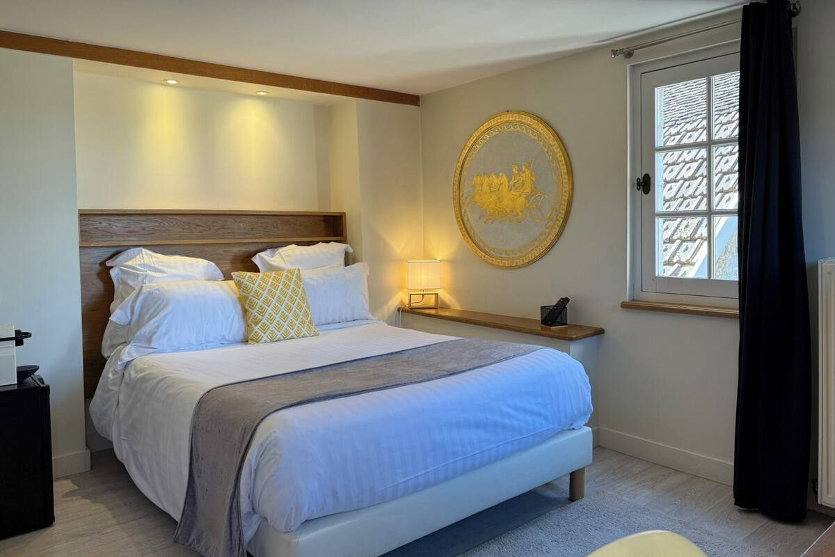 Une chambre à coucher bien rangée, avec un lit, une table de chevet, une lampe et un élément décoratif mural.