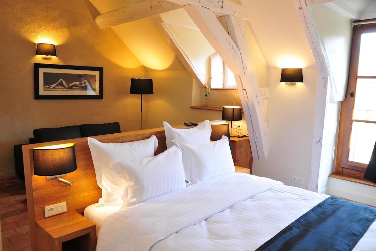 Une chambre à coucher avec une tête de lit en bois, du linge de lit blanc et deux lampes de chevet.