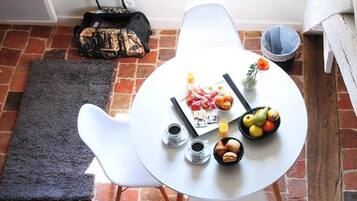 Ein runder Tisch mit Frühstücksgebäck, ein weißer Stuhl und ein Backsteinboden.