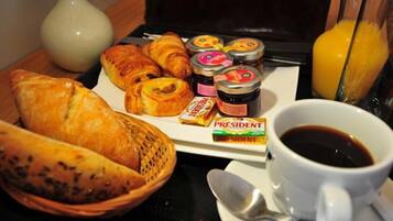 A breakfast tray with croissants, jam, a coffee cup, and a glass of orange juice.