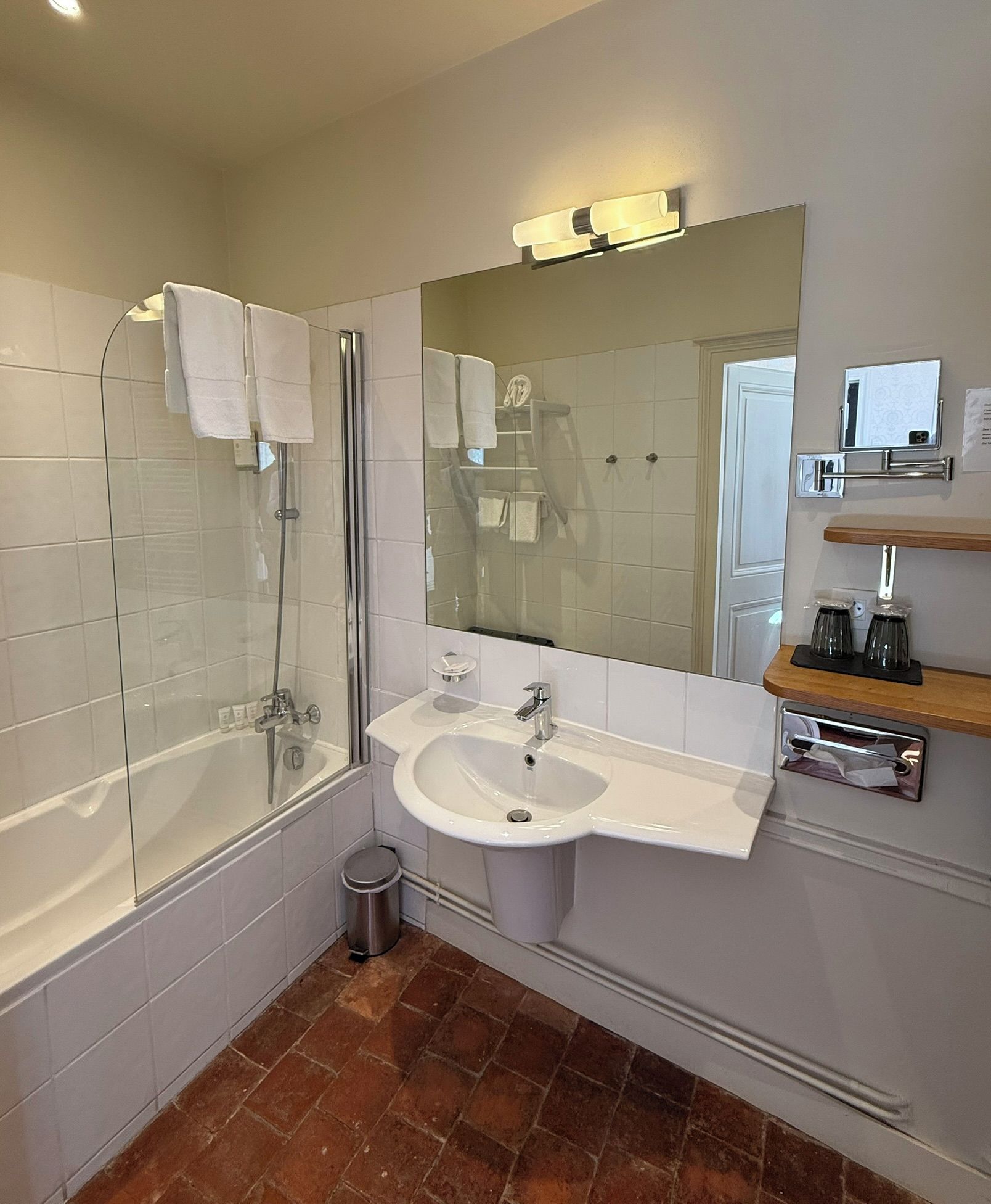 A modern bathroom with a glass-enclosed shower, a white sink, and a large mirror.