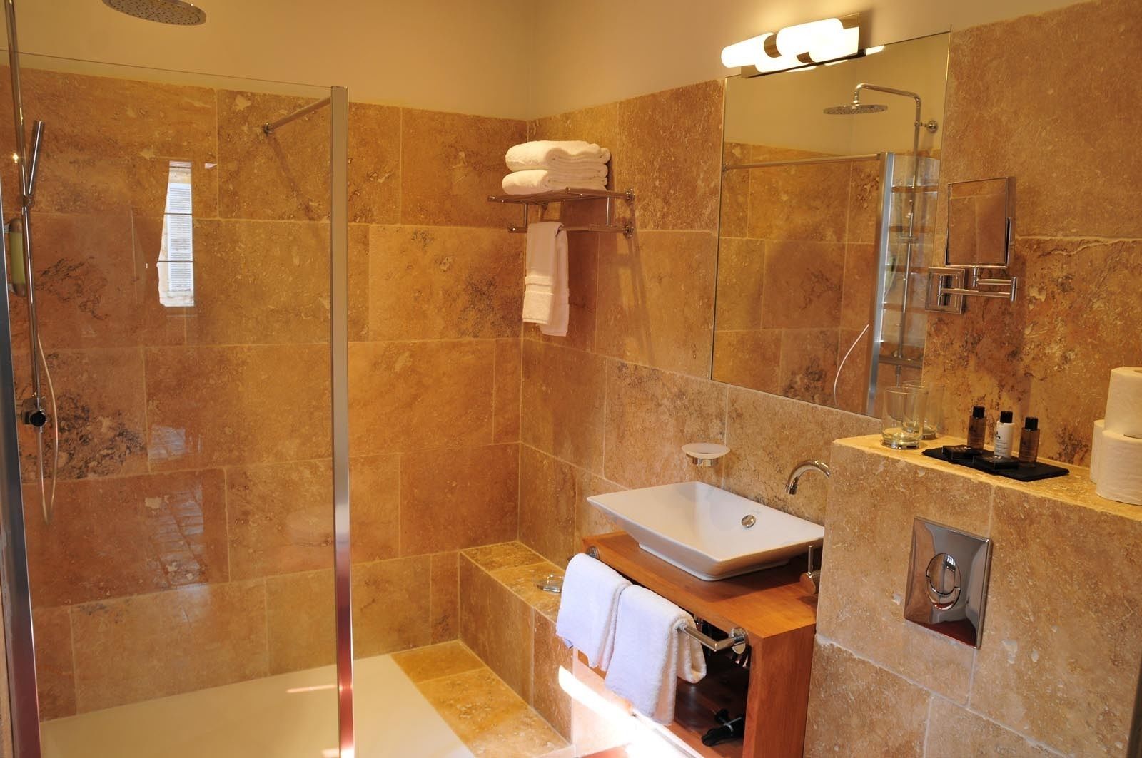 A modern bathroom with a glass-enclosed shower, a white sink, and a marble-tiled shower area.