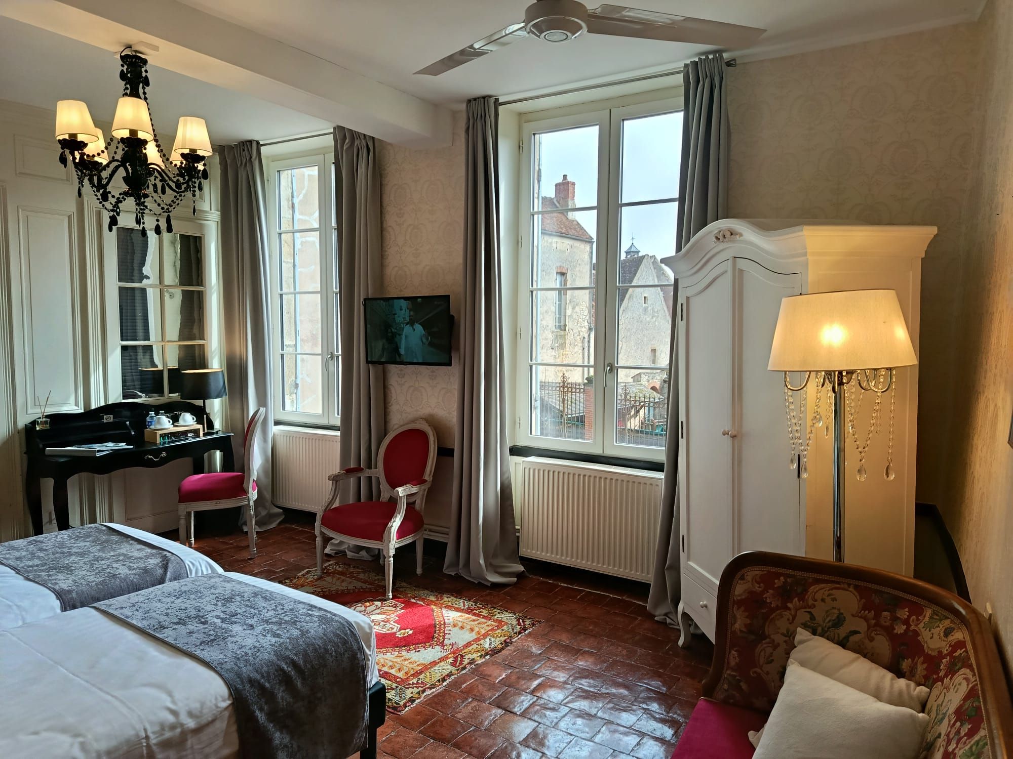 Een hotelkamer met een bed, een bureau met een piano, een stoel, een televisie en uitzicht op het omliggende gebied.
