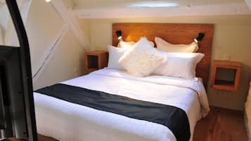 A bedroom with a wooden headboard, white bedding, a fluffy pillow, and bedside tables with lamps.