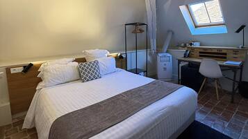 A bedroom with a bed, a desk, a chair, a window, and a skylight.