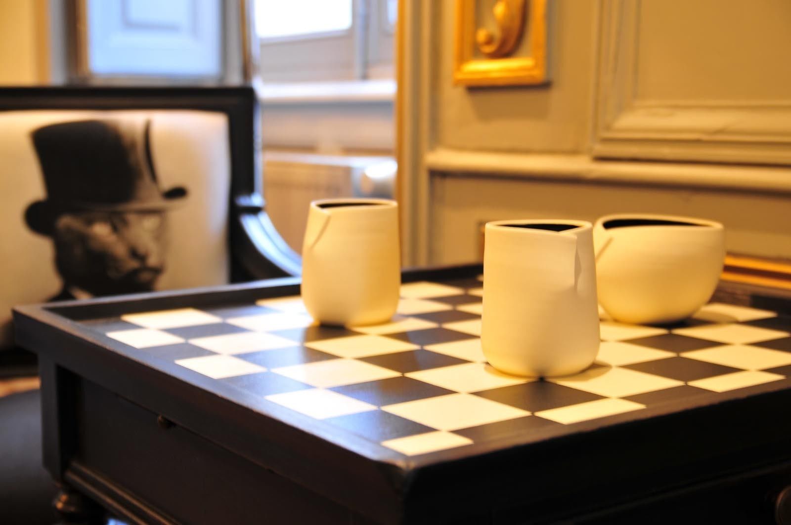 A chessboard with three vases on a table.
