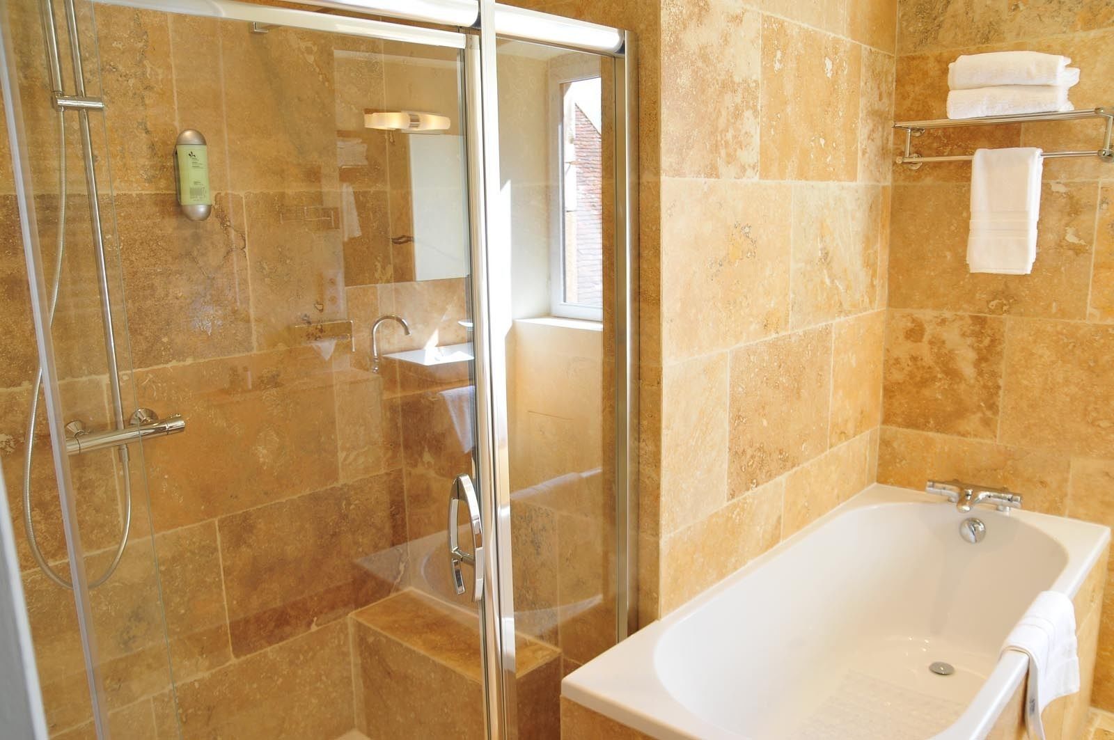 Een badkamer met een douche met glazen wand, een witte badkuip en een wastafel.