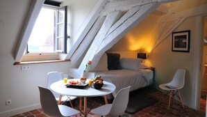 A cozy room with a bed, a dining table with chairs, and a window with a view.