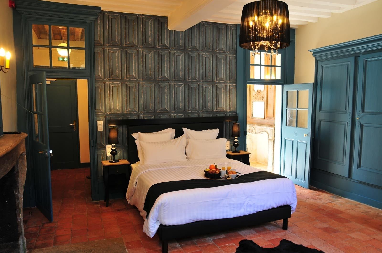 Quarto com cama grande, cabeceira de madeira, mesa de cabeceira com abajur e cômoda.