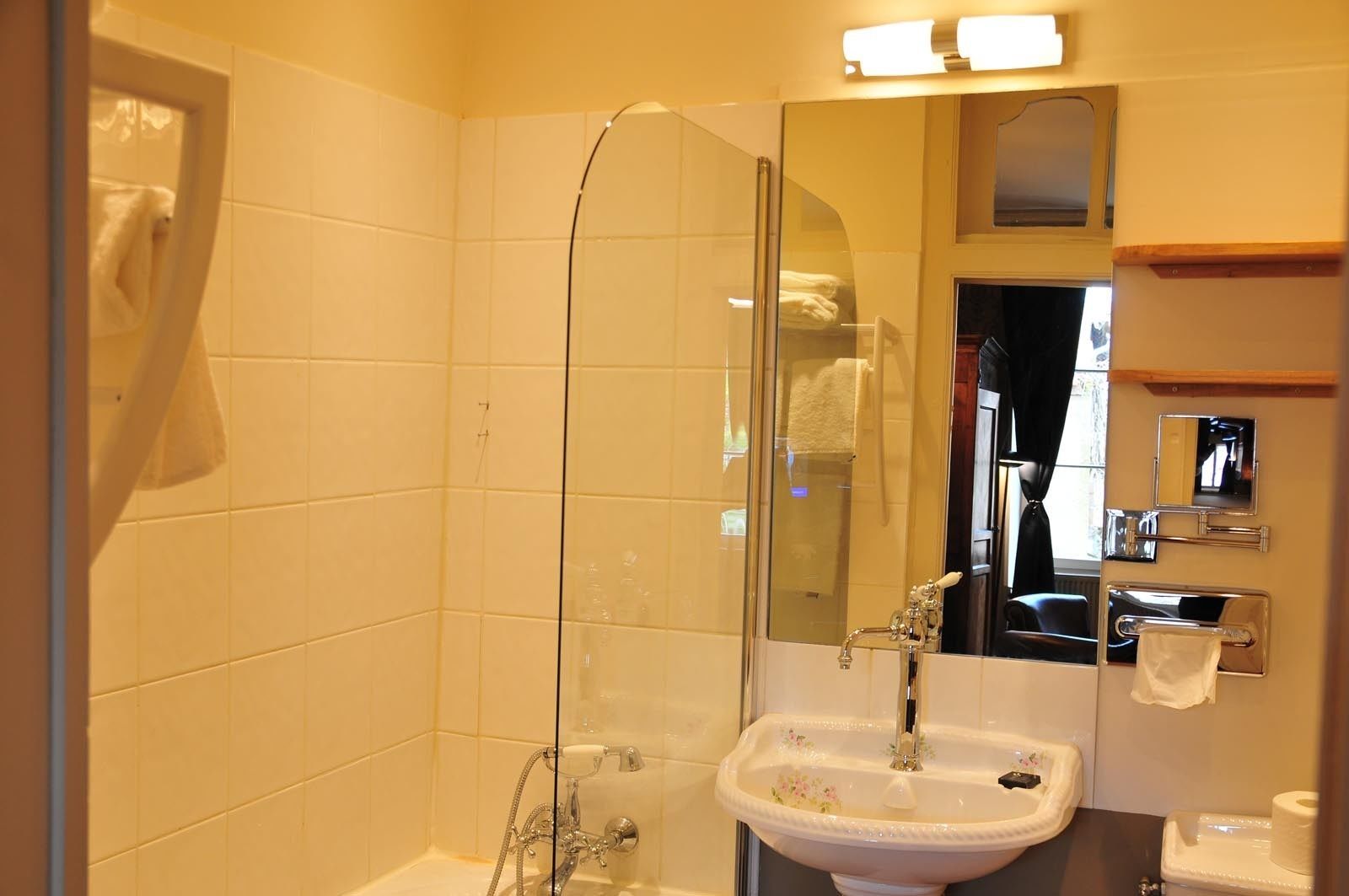 Un baño con cabina de ducha de vidrio, un lavabo y un espejo.